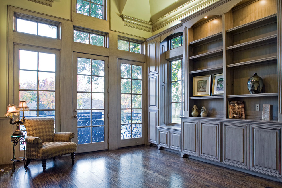 Large mediterranean home office in Dallas with a library, beige walls, dark hardwood floors, a freestanding desk and brown floor.