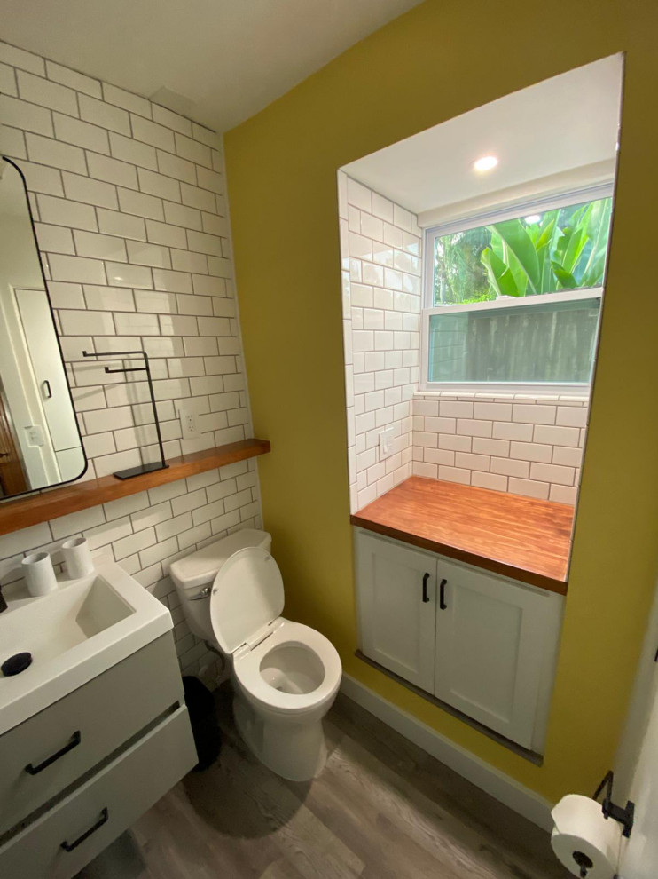 Kleines Shabby-Chic Badezimmer mit grauen Schränken, weißen Fliesen, Metrofliesen, gelber Wandfarbe, Vinylboden, grauem Boden, weißer Waschtischplatte, Wandnische, Einzelwaschbecken und schwebendem Waschtisch in Orlando