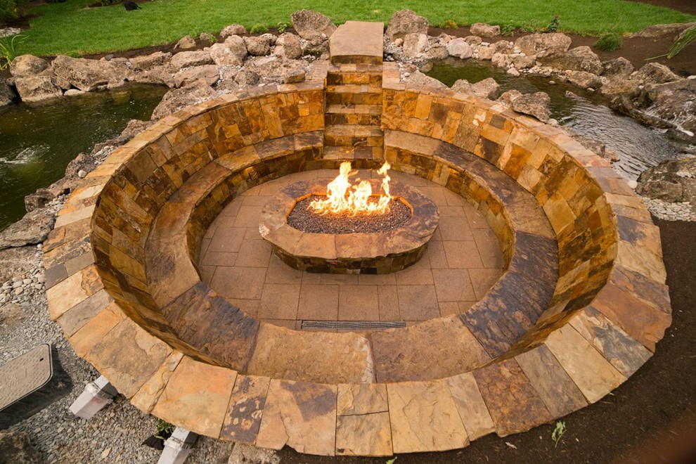 This is an example of a large craftsman full sun backyard stone landscaping with a fire pit.
