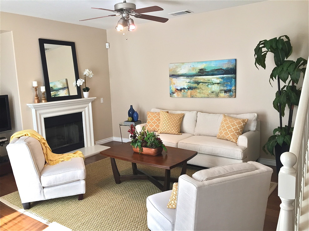 Photo of a small transitional open concept family room in Orange County with dark hardwood floors, a standard fireplace, a wood fireplace surround, a freestanding tv and beige walls.