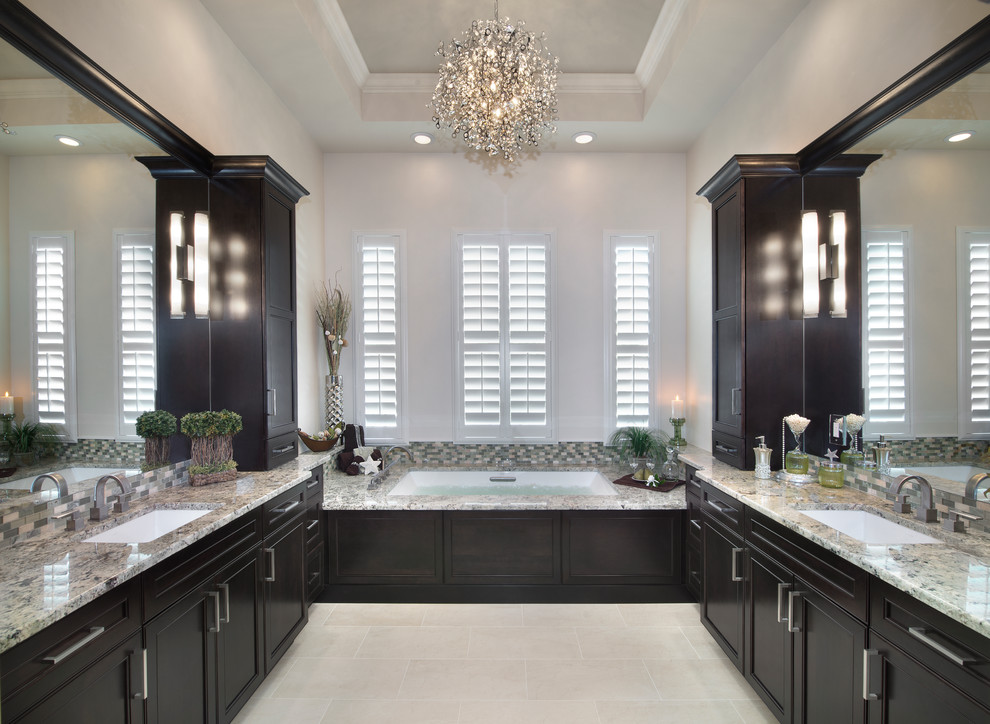Photo of a large transitional master bathroom in Miami with shaker cabinets, dark wood cabinets, beige tile, glass sheet wall, white walls, an undermount sink, granite benchtops, an undermount tub, porcelain floors and beige floor.