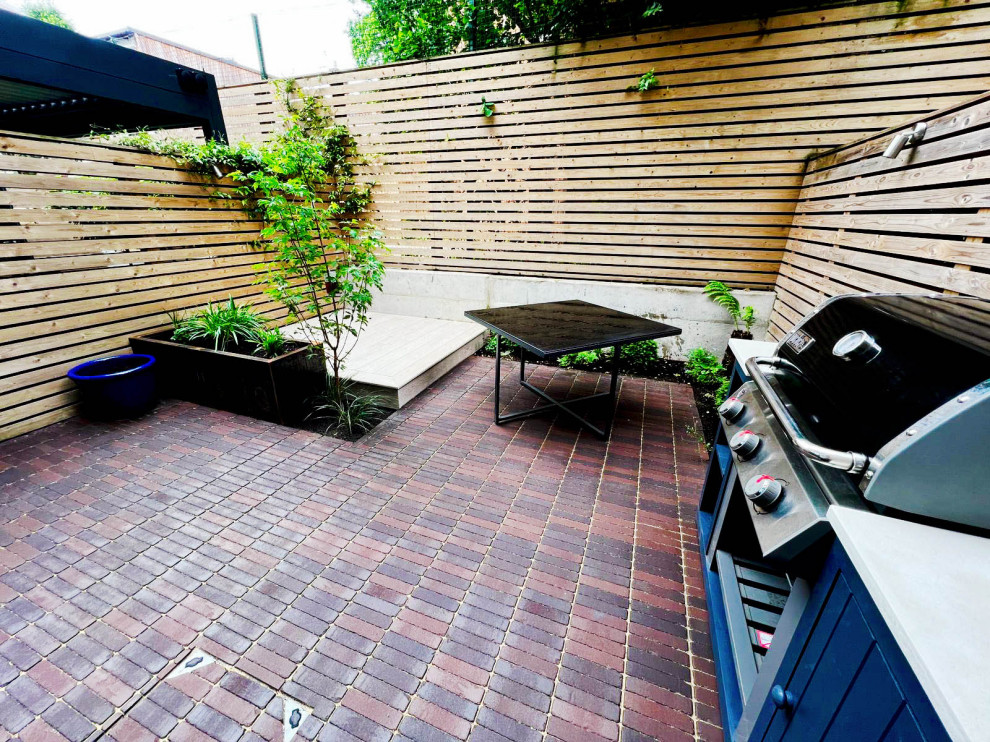 Small contemporary courtyard patio in Kent with natural stone pavers.