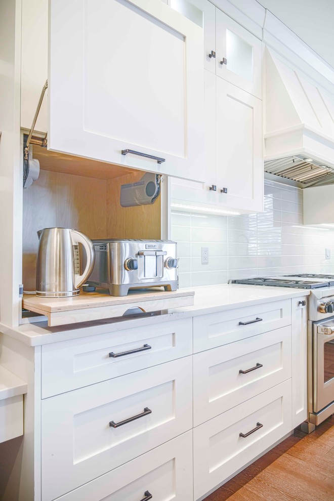 Mid-sized transitional u-shaped medium tone wood floor and brown floor kitchen photo in Calgary with an undermount sink, flat-panel cabinets, white cabinets, marble countertops, gray backsplash, ceramic backsplash, paneled appliances and an island