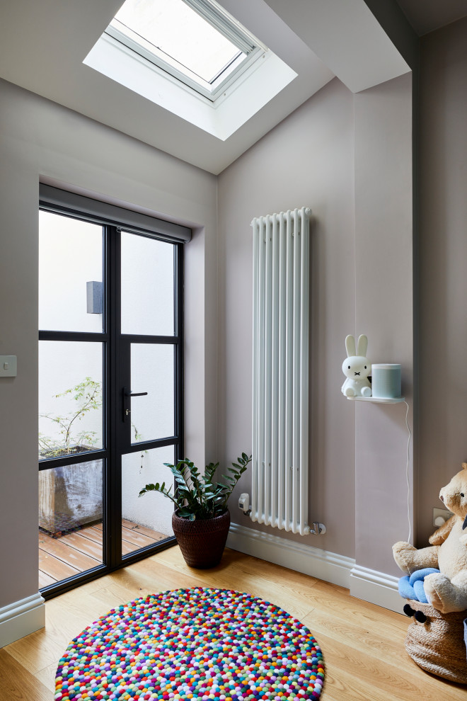 Kleines, Neutrales Modernes Babyzimmer mit beiger Wandfarbe, hellem Holzboden und braunem Boden in London