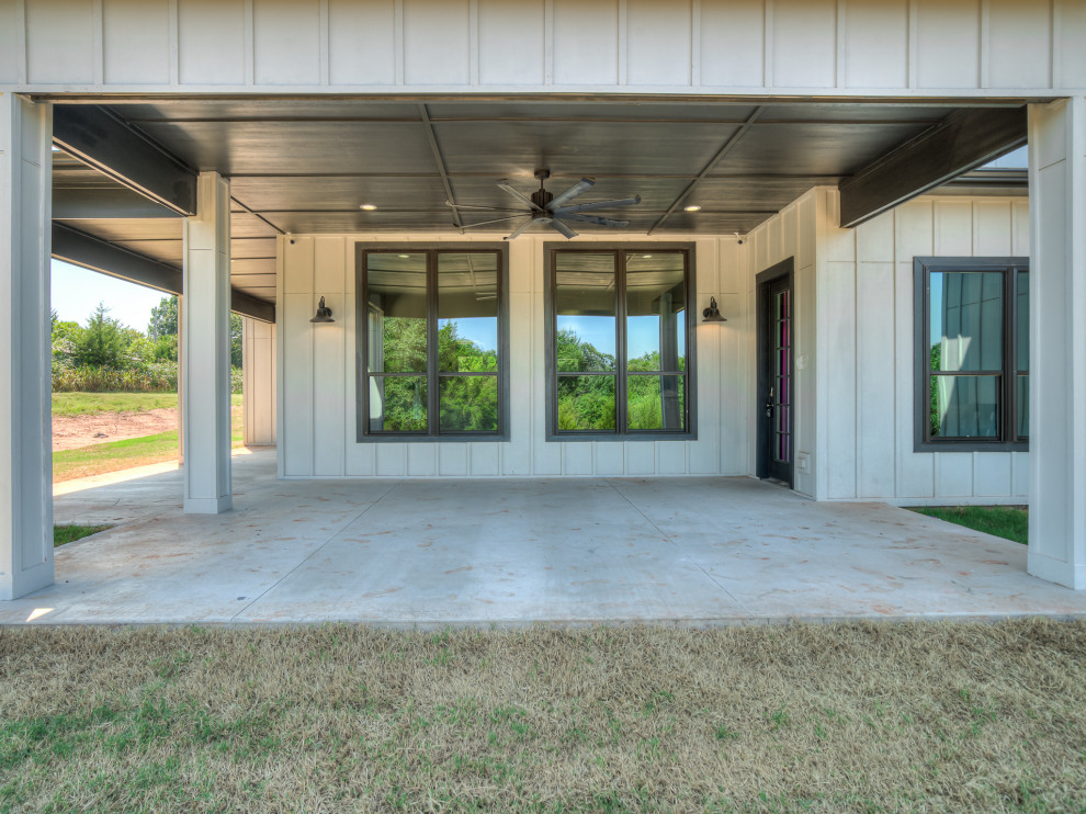 Large country back mixed railing veranda in Oklahoma City with with columns, concrete slabs and a roof extension.