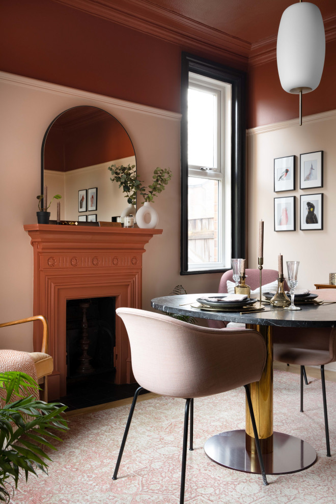 Foto di una sala da pranzo moderna con pareti rosa e camino classico