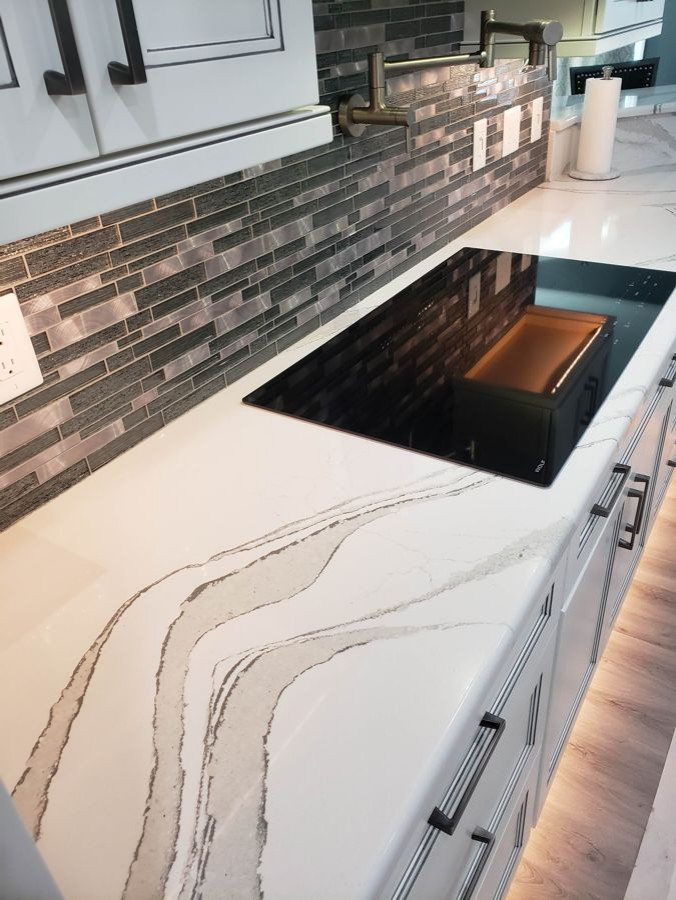 Example of a transitional u-shaped eat-in kitchen design with recessed-panel cabinets, white cabinets, quartz countertops, multicolored backsplash, mosaic tile backsplash, two islands and white countertops
