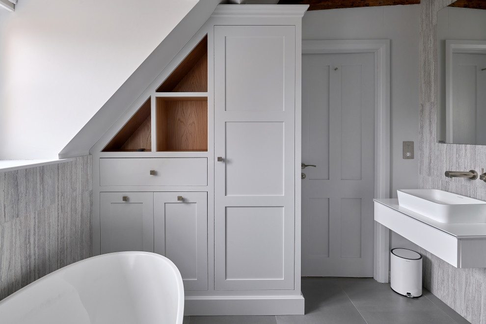 Inspiration for a small transitional master bathroom in West Midlands with white cabinets, a freestanding tub, gray tile, white walls, a vessel sink, grey floor, white benchtops, a single vanity and a floating vanity.