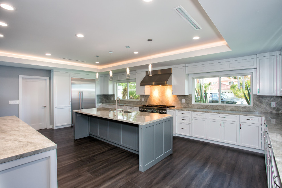 Inspiration for a large u-shaped open plan kitchen in Orange County with an undermount sink, shaker cabinets, white cabinets, marble benchtops, grey splashback, marble splashback, stainless steel appliances, dark hardwood floors, multiple islands, brown floor, grey benchtop and recessed.