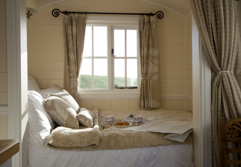 This is an example of a small country bedroom in Other with beige walls.