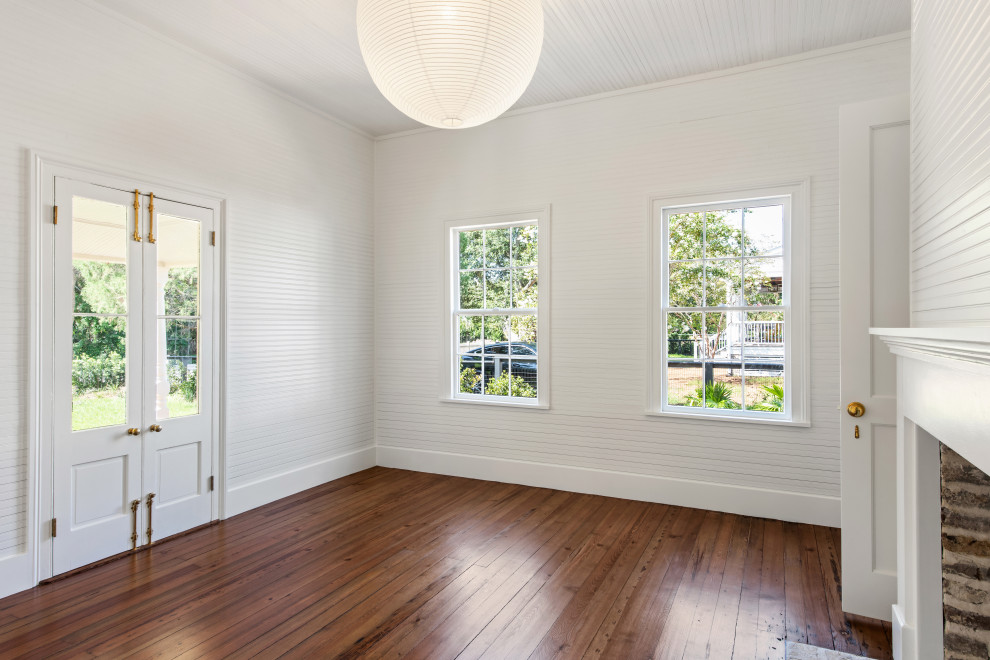 Classic guest bedroom in Charleston with white walls, medium hardwood flooring, a standard fireplace, a wooden fireplace surround, a wood ceiling and wood walls.