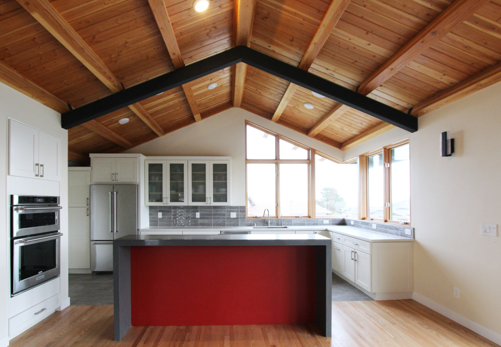 Open concept kitchen - mid-sized transitional l-shaped gray floor open concept kitchen idea with an undermount sink, shaker cabinets, white cabinets, quartz countertops, gray backsplash, ceramic backsplash, stainless steel appliances, an island and multicolored countertops