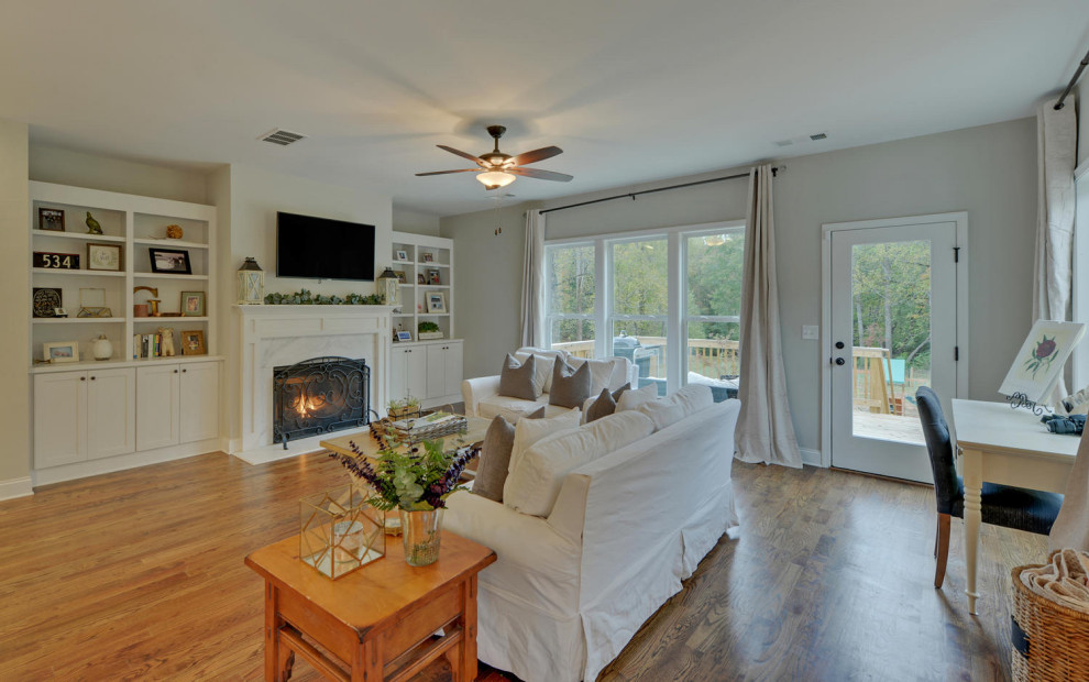 Photo of a mid-sized country open concept living room in Atlanta with beige walls, medium hardwood floors and a standard fireplace.