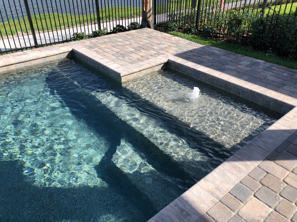 This is an example of a mid-sized traditional backyard custom-shaped pool in Orlando with brick pavers.