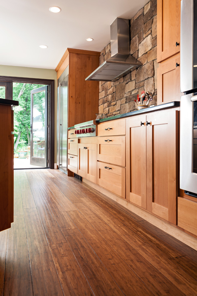Eat-in kitchen - mid-sized transitional u-shaped bamboo floor eat-in kitchen idea in Boston with an undermount sink, shaker cabinets, medium tone wood cabinets, brown backsplash, stone tile backsplash, stainless steel appliances, brown walls and an island