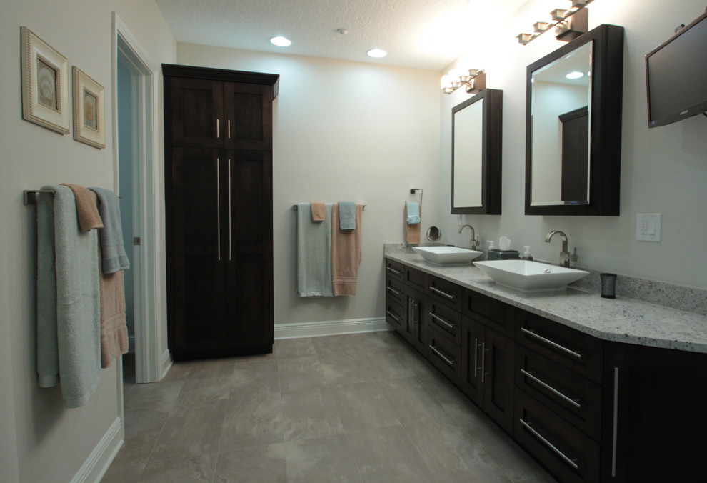 This is an example of a large beach style bathroom in Tampa with shaker cabinets, dark wood cabinets, a freestanding tub, matchstick tile, beige walls, vinyl floors, a vessel sink and granite benchtops.