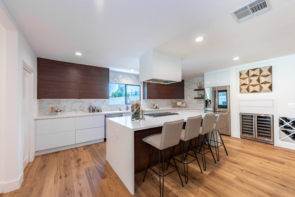 Inspiration for a large contemporary l-shaped open plan kitchen in Los Angeles with an undermount sink, flat-panel cabinets, quartz benchtops, white splashback, porcelain splashback, stainless steel appliances, light hardwood floors, with island, white benchtop, brown cabinets and brown floor.