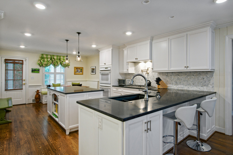 Large transitional u-shaped dark wood floor eat-in kitchen photo with an undermount sink, beaded inset cabinets, white cabinets, white backsplash, marble backsplash, white appliances and an island