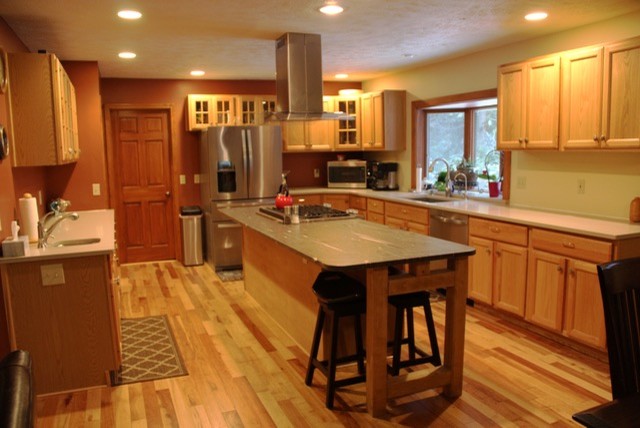 This is an example of a large country u-shaped kitchen in Other with an undermount sink, beaded inset cabinets, medium wood cabinets, granite benchtops, stainless steel appliances, medium hardwood floors and with island.