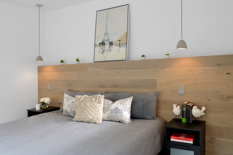 Mid-sized contemporary master bedroom in Toronto with white walls, light hardwood floors, a two-sided fireplace, a plaster fireplace surround and beige floor.