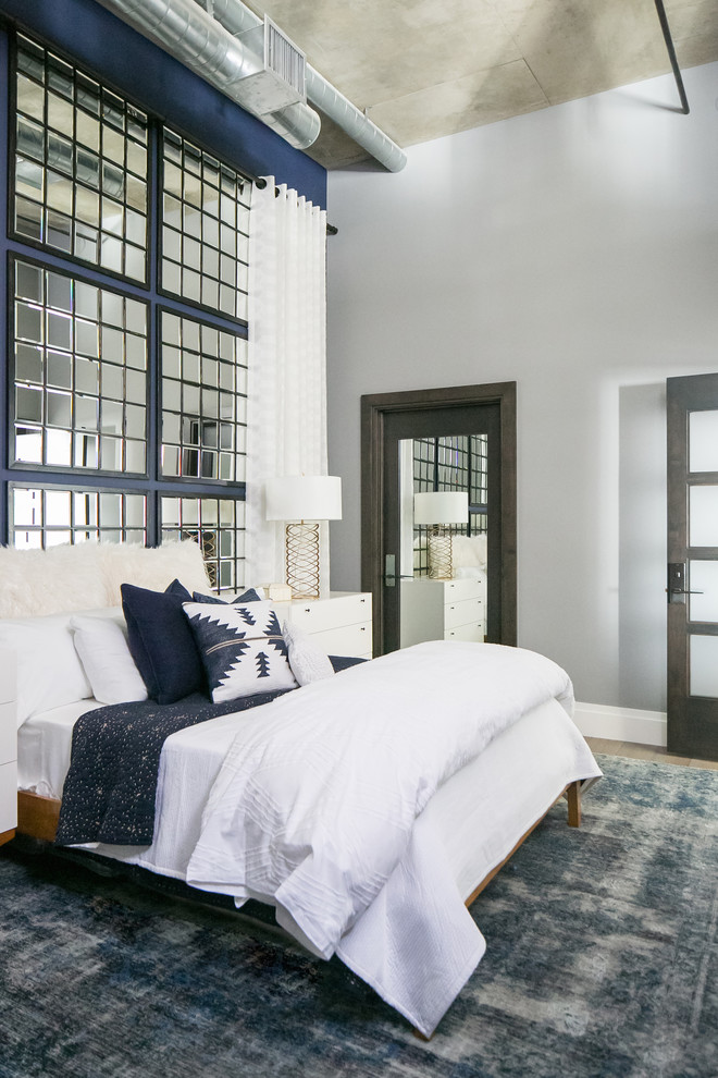This is an example of a mid-sized industrial guest bedroom in Denver with blue walls, medium hardwood floors and grey floor.