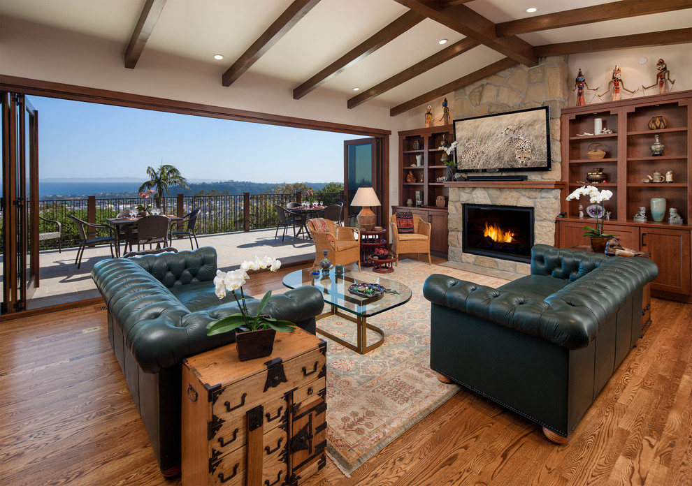 Inspiration for a mid-sized asian open concept living room in Santa Barbara with white walls, medium hardwood floors, a standard fireplace, a stone fireplace surround and a wall-mounted tv.