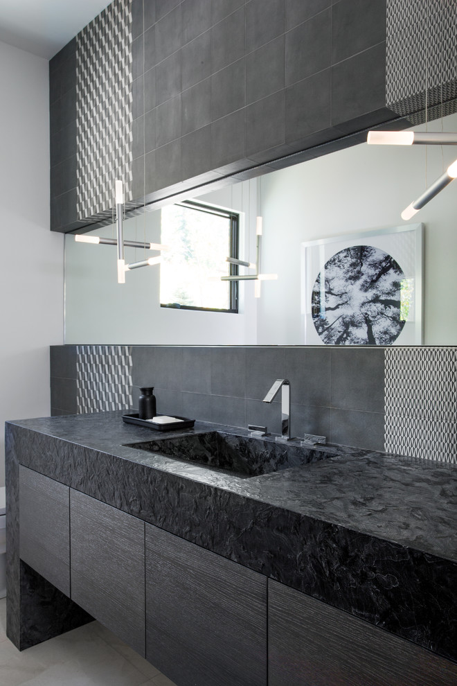 This is an example of a contemporary powder room in Salt Lake City with an integrated sink, flat-panel cabinets, dark wood cabinets and gray tile.