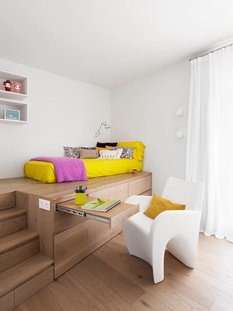 Photo of a large contemporary gender-neutral kids' bedroom for kids 4-10 years old in Barcelona with white walls and medium hardwood floors.