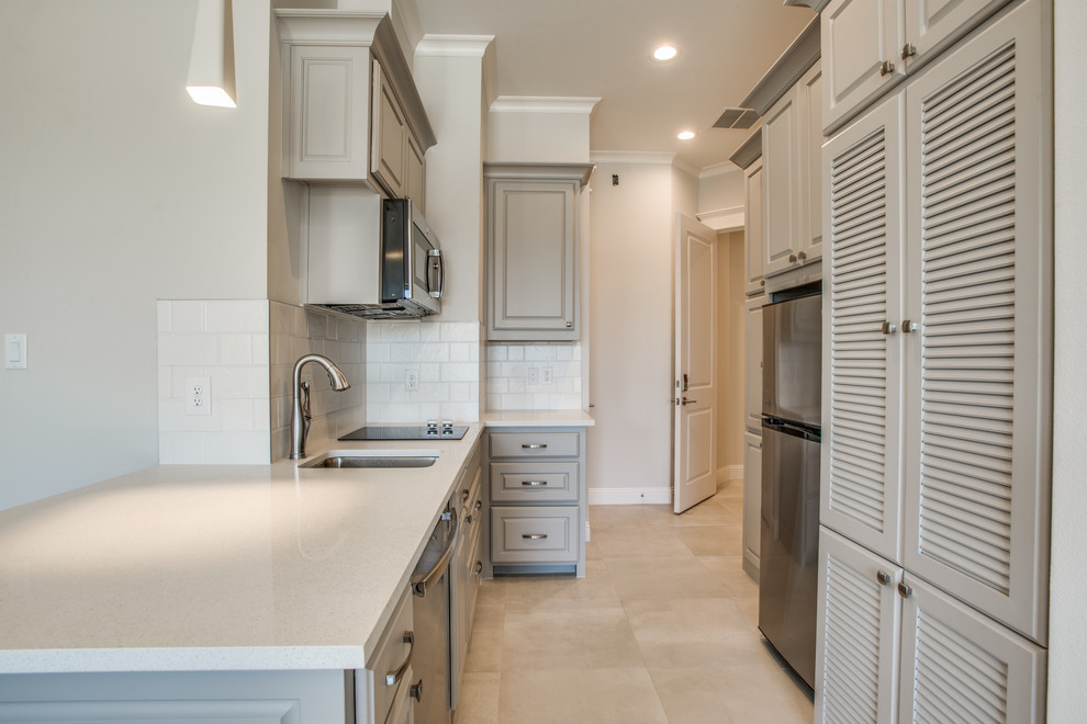 Photo of a mid-sized transitional galley separate kitchen in Dallas with an undermount sink, raised-panel cabinets, grey cabinets, stainless steel appliances and no island.