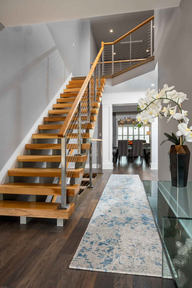 Diseño de escalera suspendida minimalista extra grande con escalones de madera, contrahuellas de madera y barandilla de cable