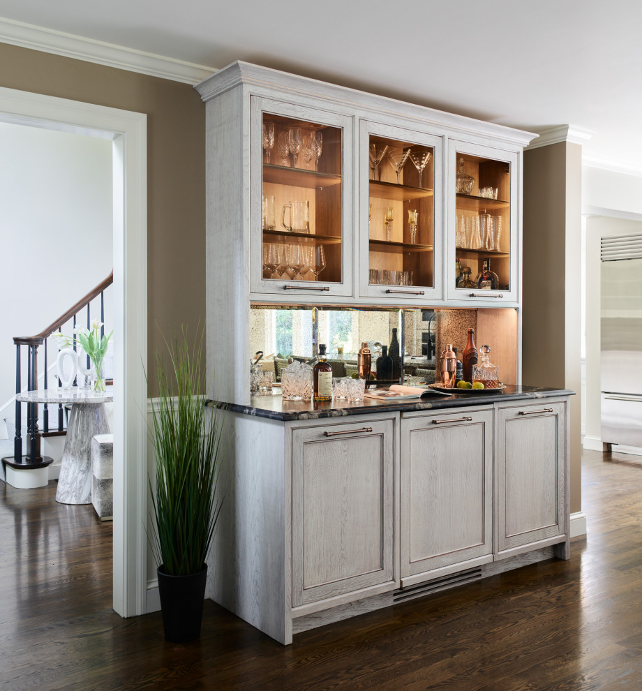 Design ideas for a country home bar in Boston with glass-front cabinets, distressed cabinets, granite benchtops, mirror splashback and black benchtop.