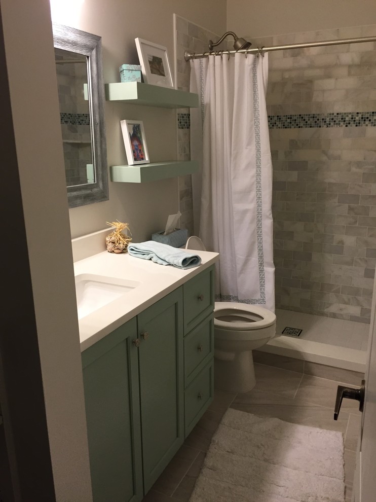 Photo of a mid-sized transitional 3/4 bathroom in Miami with recessed-panel cabinets, green cabinets, an alcove shower, a two-piece toilet, gray tile, subway tile, beige walls, porcelain floors, an undermount sink and engineered quartz benchtops.