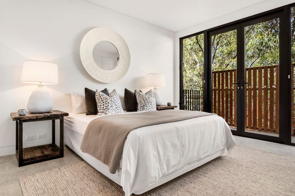 Large beach style master bedroom in Sydney with white walls and grey floor.