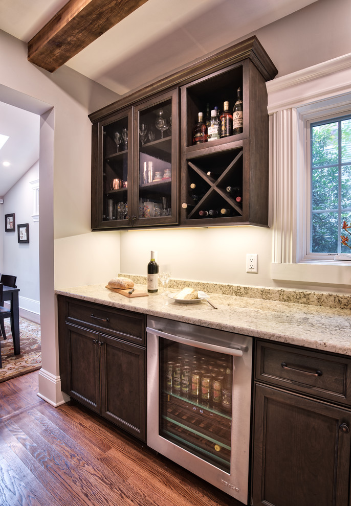 This is an example of a mid-sized country single-wall wet bar in New York with a drop-in sink, brown cabinets, granite benchtops, painted wood floors, brown floor and multi-coloured benchtop.