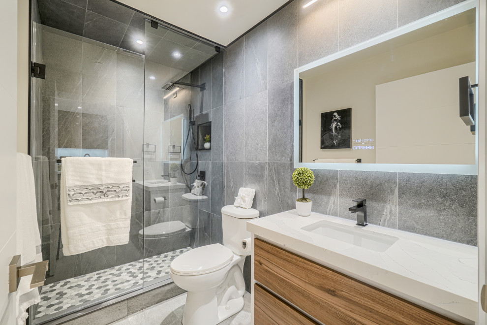 Immagine di una stanza da bagno minimalista con ante lisce, ante in legno scuro, piastrelle grigie, piastrelle in ceramica, lavabo da incasso, top grigio, nicchia, un lavabo e mobile bagno sospeso