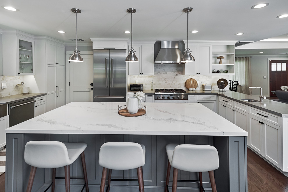 Photo of a mid-sized transitional u-shaped open plan kitchen in San Francisco with a farmhouse sink, shaker cabinets, white cabinets, quartz benchtops, white splashback, marble splashback, stainless steel appliances, dark hardwood floors, with island, brown floor and white benchtop.