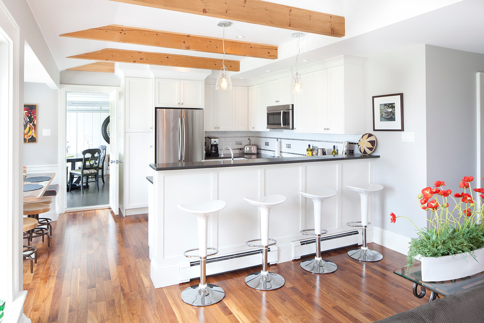 Photo of a country u-shaped eat-in kitchen in Toronto with shaker cabinets, white cabinets, multi-coloured splashback, mosaic tile splashback, stainless steel appliances, medium hardwood floors and a peninsula.