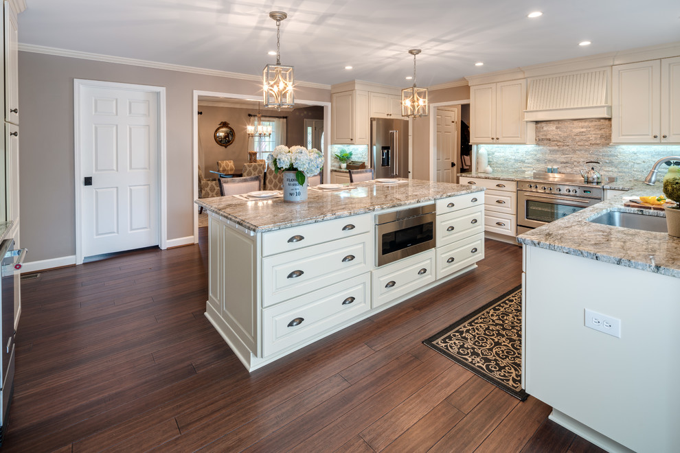 Large traditional u-shaped eat-in kitchen in Atlanta with an undermount sink, raised-panel cabinets, white cabinets, granite benchtops, stainless steel appliances, bamboo floors, with island, brown floor, brown splashback, stone tile splashback and multi-coloured benchtop.
