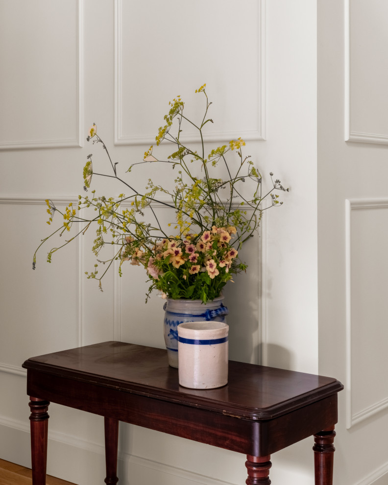 Small elegant medium tone wood floor and wainscoting hallway photo in Seattle with white walls