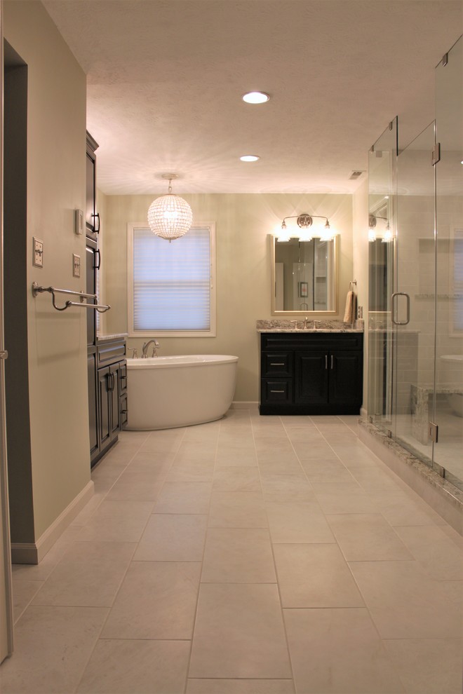 This is an example of a large transitional master bathroom in Indianapolis with raised-panel cabinets, dark wood cabinets, a freestanding tub, a double shower, a two-piece toilet, white tile, mosaic tile, green walls, porcelain floors, an undermount sink, granite benchtops, white floor and a hinged shower door.