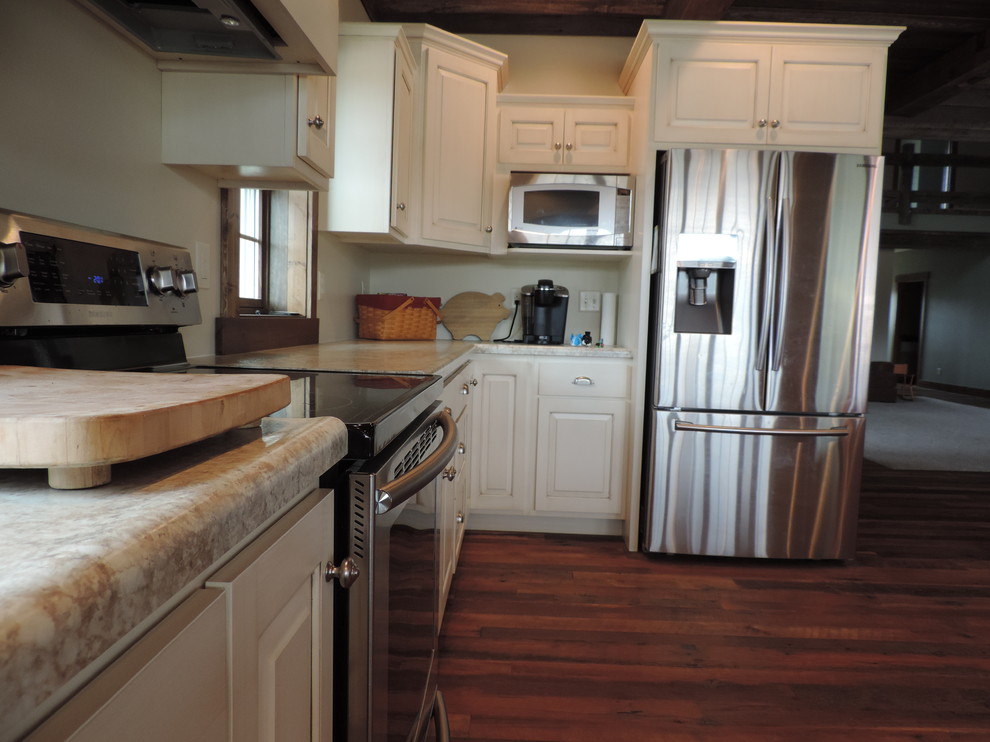 Large mountain style u-shaped dark wood floor eat-in kitchen photo with a farmhouse sink, raised-panel cabinets, white cabinets, marble countertops, stainless steel appliances and an island