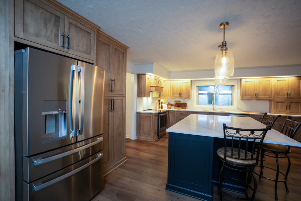 Example of a large transitional l-shaped medium tone wood floor and brown floor eat-in kitchen design with a single-bowl sink, shaker cabinets, medium tone wood cabinets, quartz countertops, white backsplash, quartz backsplash, stainless steel appliances, an island and white countertops