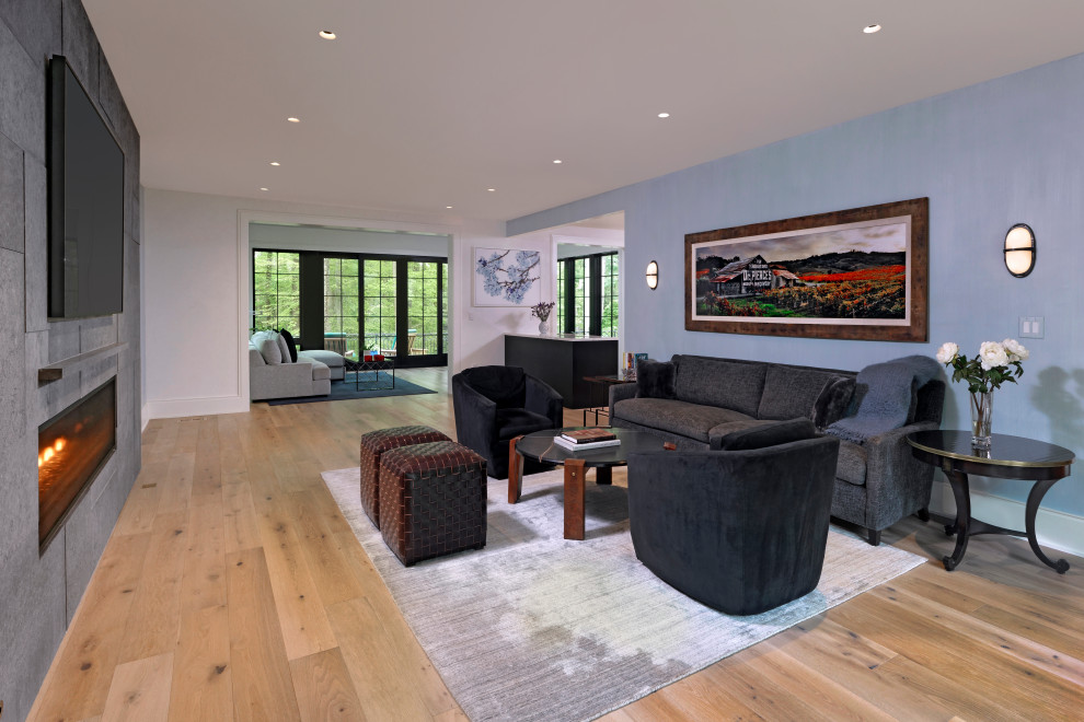 This is an example of an expansive contemporary open concept family room in DC Metro with blue walls, light hardwood floors, a ribbon fireplace, a concrete fireplace surround, a wall-mounted tv and brown floor.