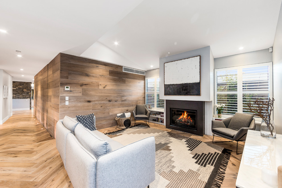 Mid-sized modern formal open concept living room in Melbourne with grey walls, light hardwood floors, a standard fireplace, a plaster fireplace surround, no tv and brown floor.