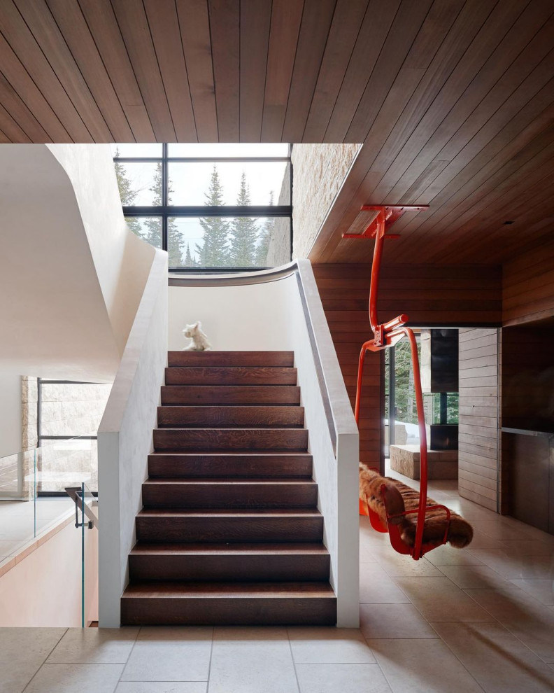 Стильный дизайн: огромная изогнутая деревянная лестница в стиле рустика с деревянными ступенями и деревянными перилами - последний тренд