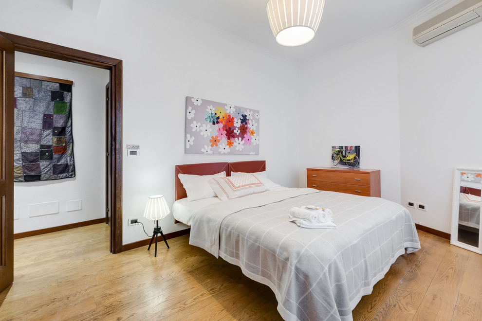 Photo of a large contemporary master bedroom in Rome with white walls and light hardwood floors.