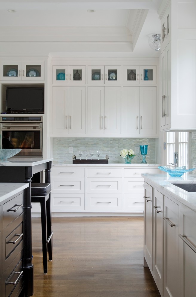 Photo of a large transitional l-shaped separate kitchen in Boston with an undermount sink, shaker cabinets, white cabinets, marble benchtops, multi-coloured splashback, stainless steel appliances, glass tile splashback, dark hardwood floors and with island.