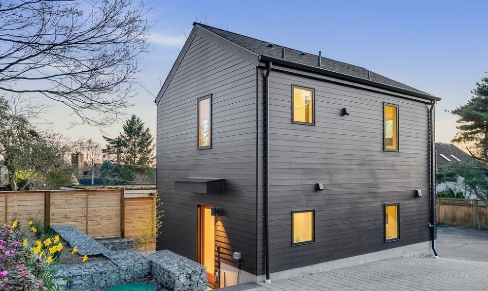 Immagine della micro casa piccola scandinava a due piani con rivestimento con lastre in cemento, tetto a capanna, copertura a scandole e tetto nero