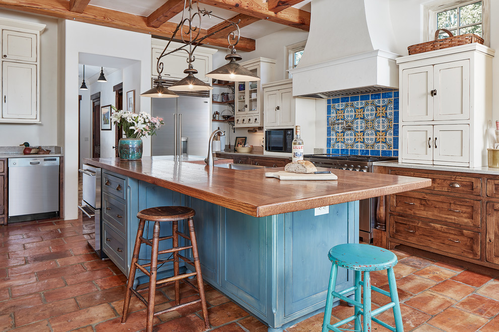 Design ideas for a large mediterranean u-shaped kitchen in Atlanta with shaker cabinets, blue cabinets, wood benchtops, multi-coloured splashback, stainless steel appliances, with island, a farmhouse sink, terra-cotta floors and brown benchtop.