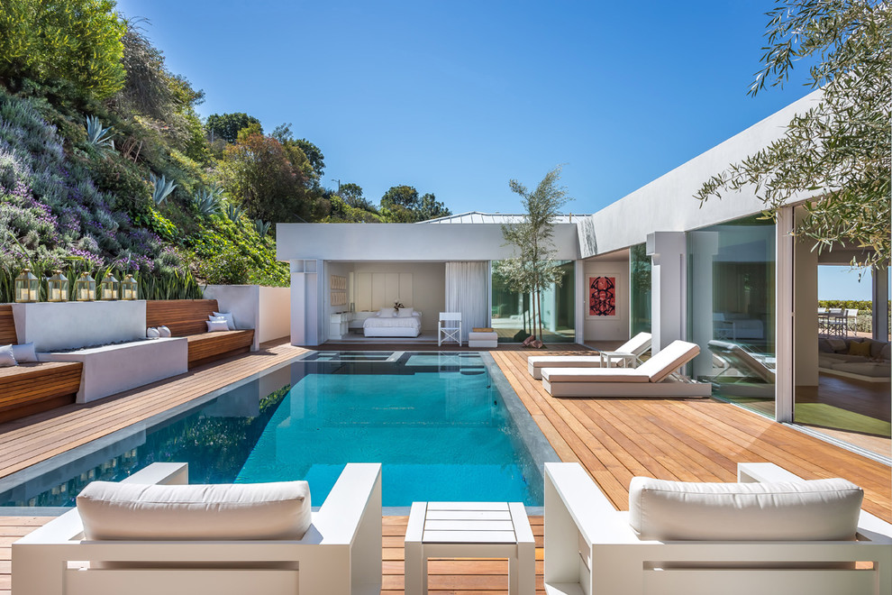Contemporary backyard rectangular infinity pool in Los Angeles with a hot tub and decking.